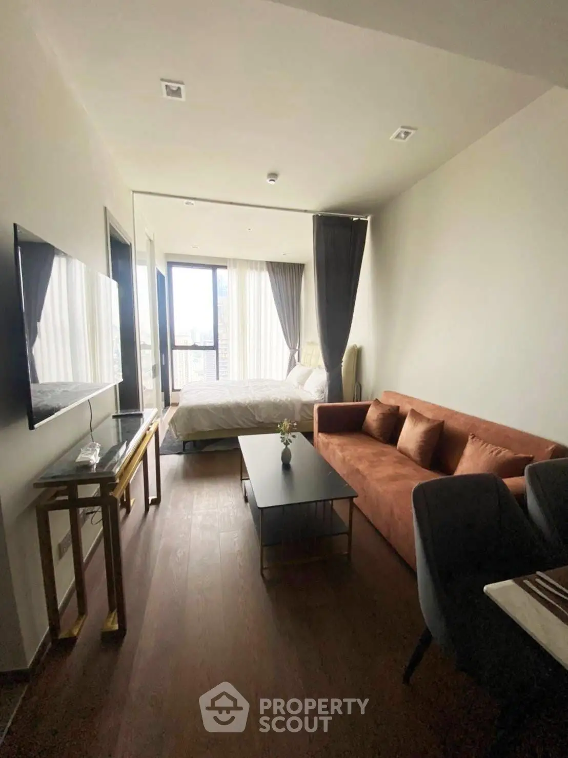 Modern studio apartment with open layout, featuring a cozy living area and a bright bedroom with city views.