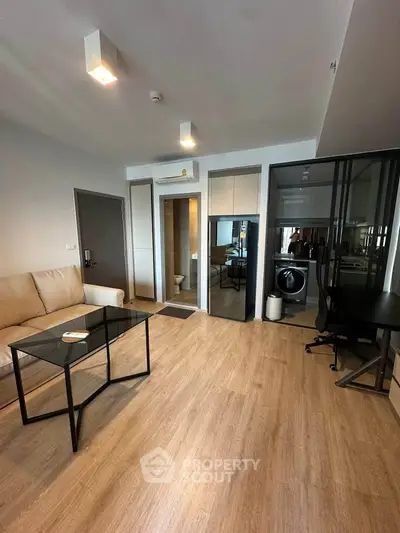 Modern living room with sleek furniture and integrated laundry area in stylish apartment.