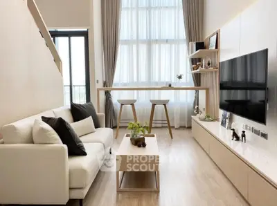 Modern living room with high ceilings, large windows, and stylish decor in a contemporary apartment.