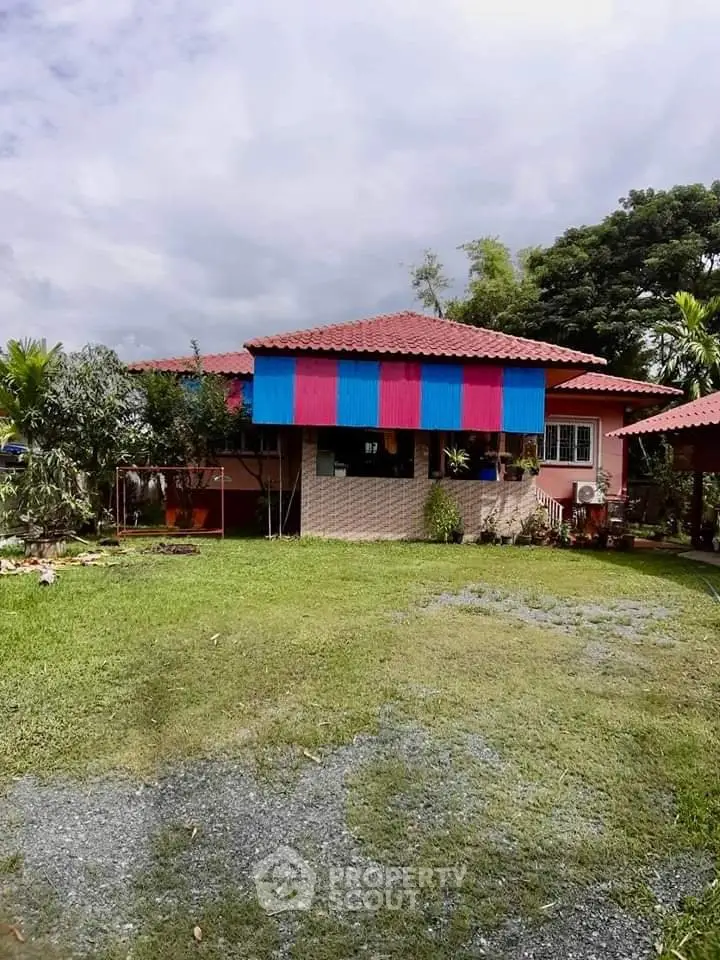 Charming single-story house with vibrant awning and lush green garden, perfect for serene living.