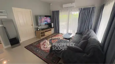 Cozy living room with plush sofa, large TV, and elegant curtains.