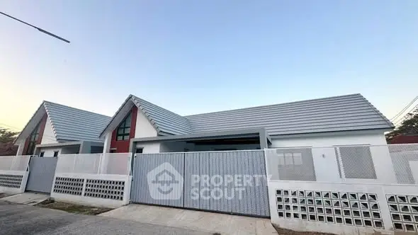Modern single-story house with sleek roof design and gated entrance.