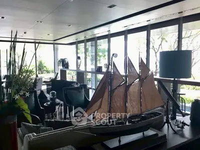Luxurious living room with nautical decor and large windows offering garden views.