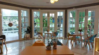 Charming cafe-style dining area with large windows and garden view, perfect for relaxation and social gatherings.