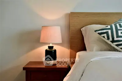 Cozy bedroom with stylish lamp and wooden nightstand, perfect for relaxation.