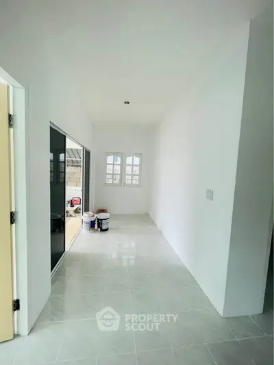 Bright hallway with tiled floor and sliding glass doors leading to outdoor space.