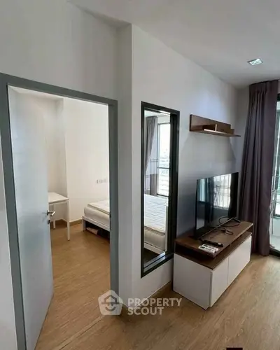 Modern apartment interior with bedroom and living area, featuring sleek design and natural light.