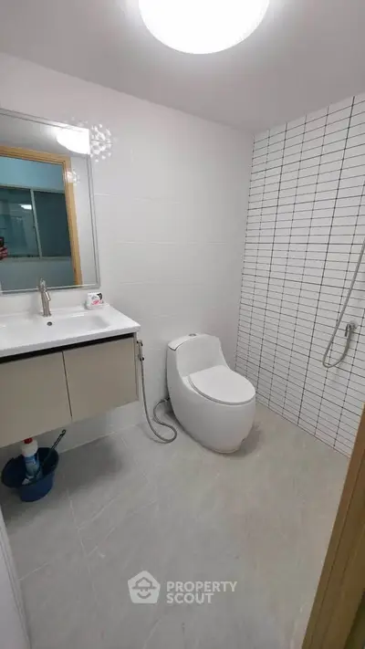 Modern bathroom with sleek fixtures and tiled walls, featuring a stylish toilet and vanity.