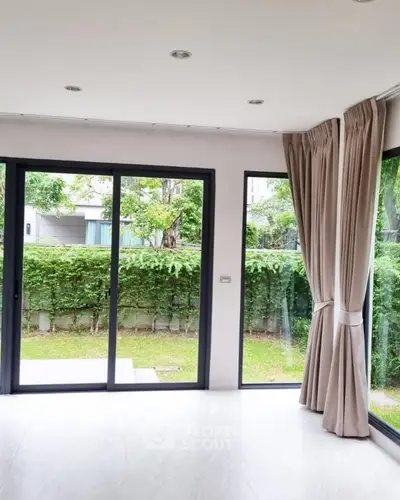 Bright living room with large windows overlooking lush garden