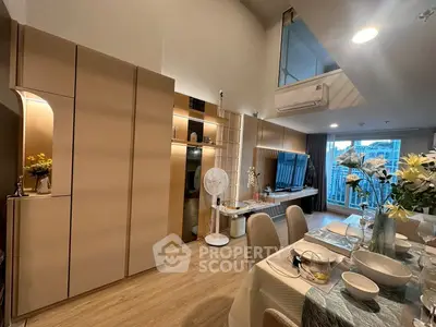 Modern living room with stylish dining area and large TV, featuring elegant decor and open layout.