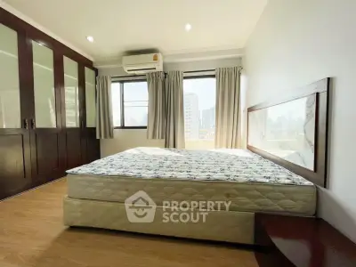 Spacious bedroom with large windows and built-in wardrobe in modern apartment.