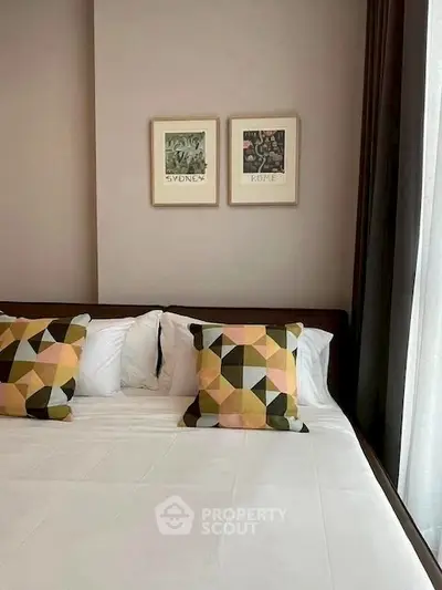 Stylish bedroom with geometric pillows and framed art, perfect for modern living.