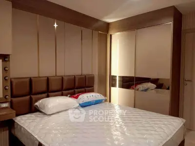 Modern bedroom with stylish padded headboard and mirrored wardrobe in a cozy apartment.