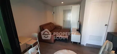 Cozy living room with brown leather sofa and modern decor in compact apartment.