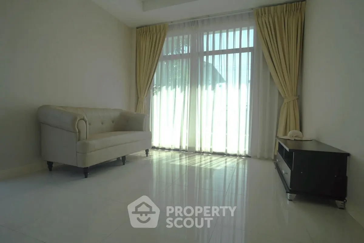 Spacious living room with elegant sofa and large window with curtains