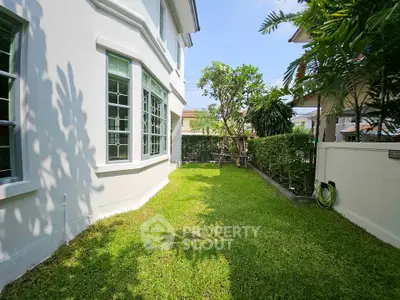 Charming garden view of a modern home with lush greenery and large windows.