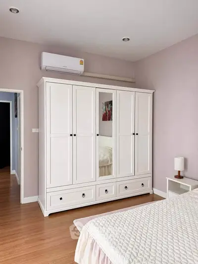 Spacious bedroom with elegant white wardrobe and cozy bed setup