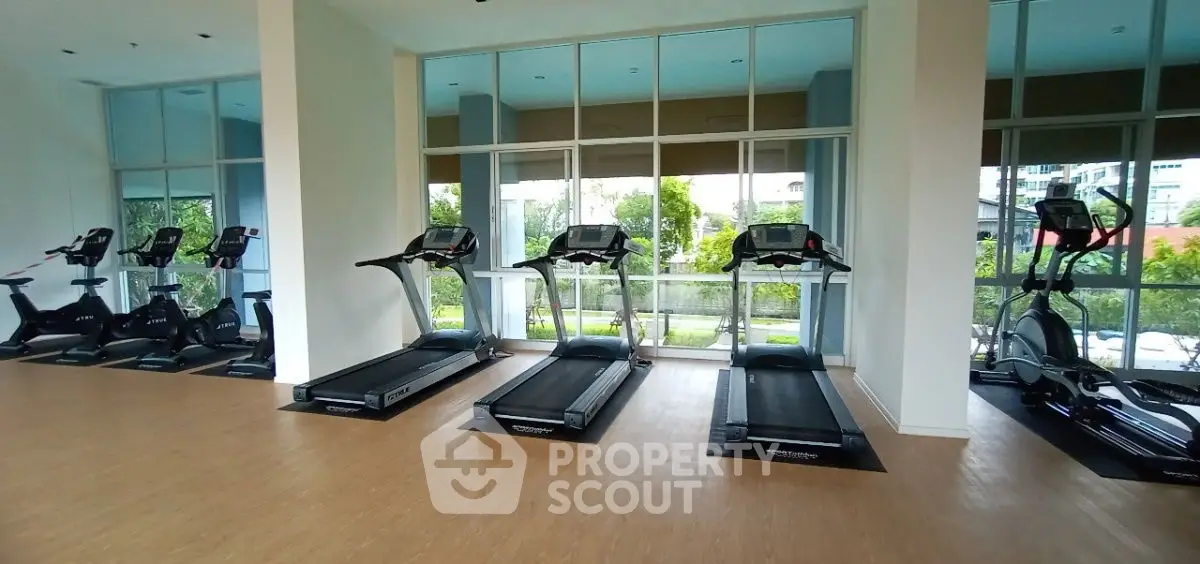 Modern gym with treadmills and exercise bikes in a bright, spacious room with large windows.