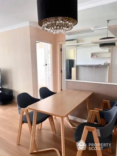 Modern dining area with stylish wooden table and chairs, elegant lighting, and open kitchen layout.