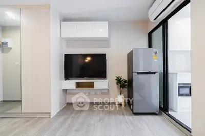 Modern living room with sleek TV setup and stainless steel fridge