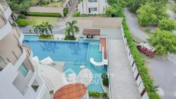Stunning aerial view of luxurious apartment pool with lush greenery.