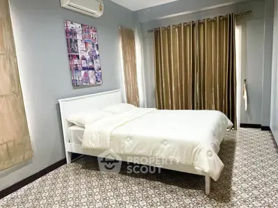 Spacious bedroom with modern decor and natural light, featuring a comfortable bed and stylish curtains.