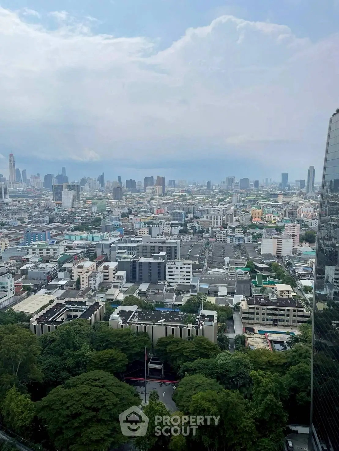 Stunning cityscape view from high-rise building showcasing urban skyline and lush greenery.