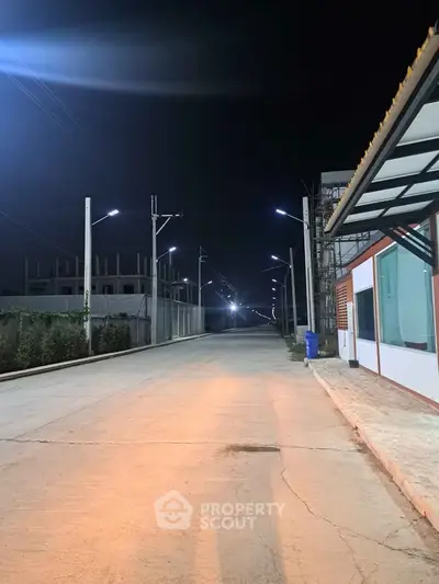 Night view of a modern building exterior with street lighting and construction site.