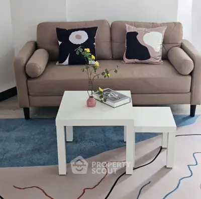 Stylish living room with modern beige sofa and artistic cushions, complemented by a chic white coffee table.