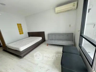 Modern bedroom with minimalist design, featuring a bed, sofa, and air conditioning.