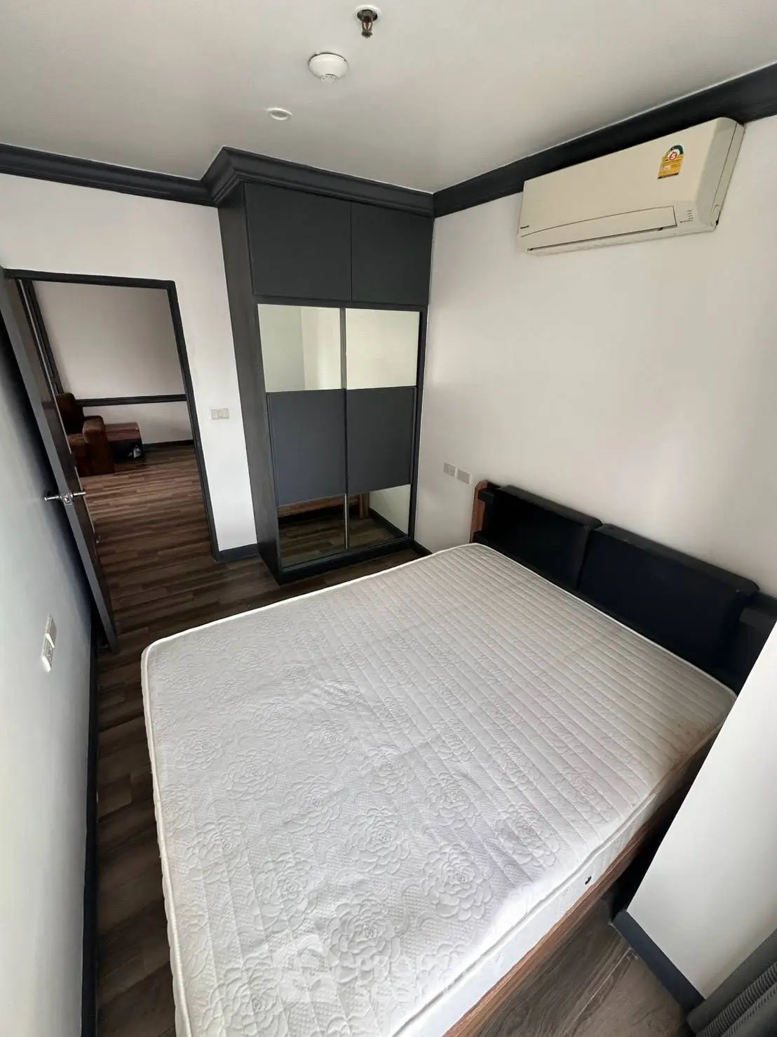 Modern bedroom with sleek design, mirrored wardrobe, and air conditioning unit.