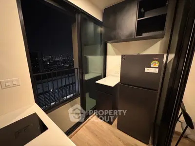 Modern kitchen with balcony view, featuring sleek appliances and night cityscape.