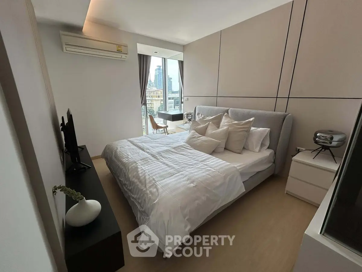 Modern bedroom with city view, featuring elegant decor and natural light, perfect for urban living.