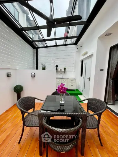 Stylish enclosed balcony with glass roof and modern outdoor furniture