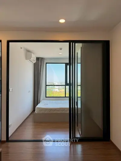 Modern bedroom with large window and sliding glass door, offering a bright and airy atmosphere.