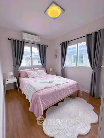 Charming bedroom with pink bedding, cozy rug, and ample natural light from large windows.