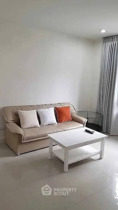 Modern living room with beige sofa, white coffee table, and elegant curtains.