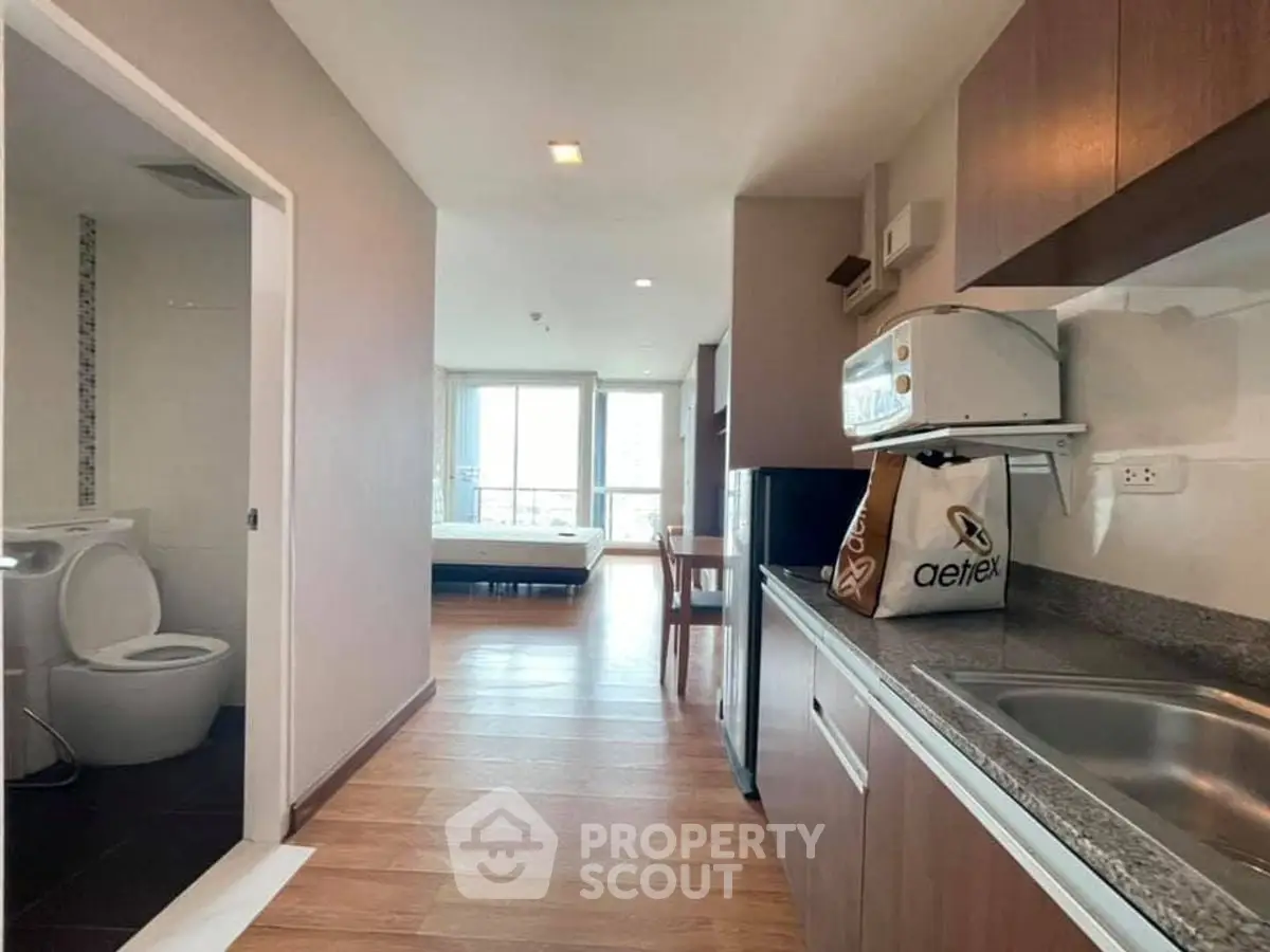 Modern apartment interior with kitchen and bathroom, featuring sleek design and natural light.