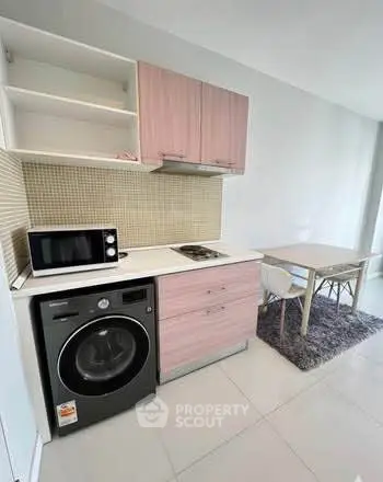 Modern compact kitchen with washing machine and dining area in sleek apartment.