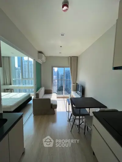 Modern apartment with open layout, featuring a cozy living area and stunning city view from the balcony.