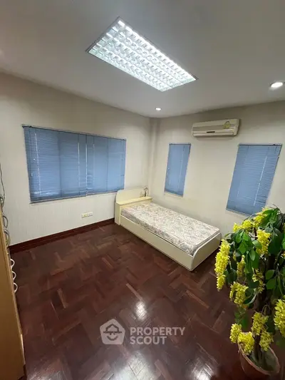 Cozy bedroom with single bed, air conditioning, and wooden flooring.