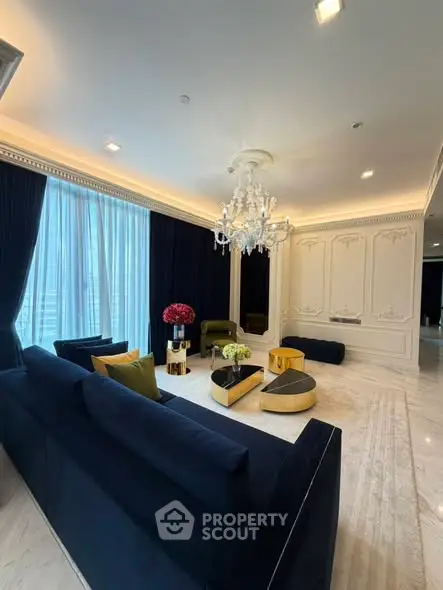 Luxurious living room with elegant chandelier and plush navy sofas in a sophisticated setting.