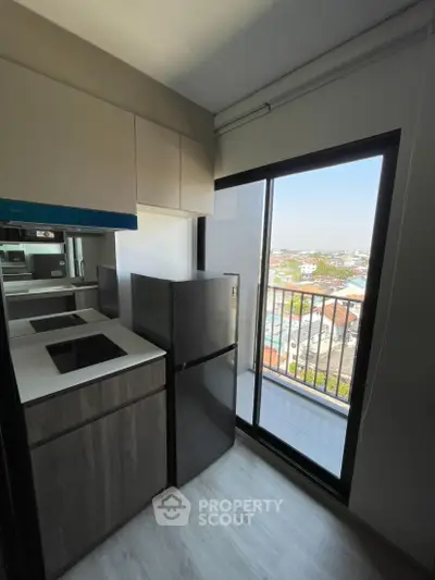 Modern kitchen with sleek appliances and balcony view in high-rise apartment