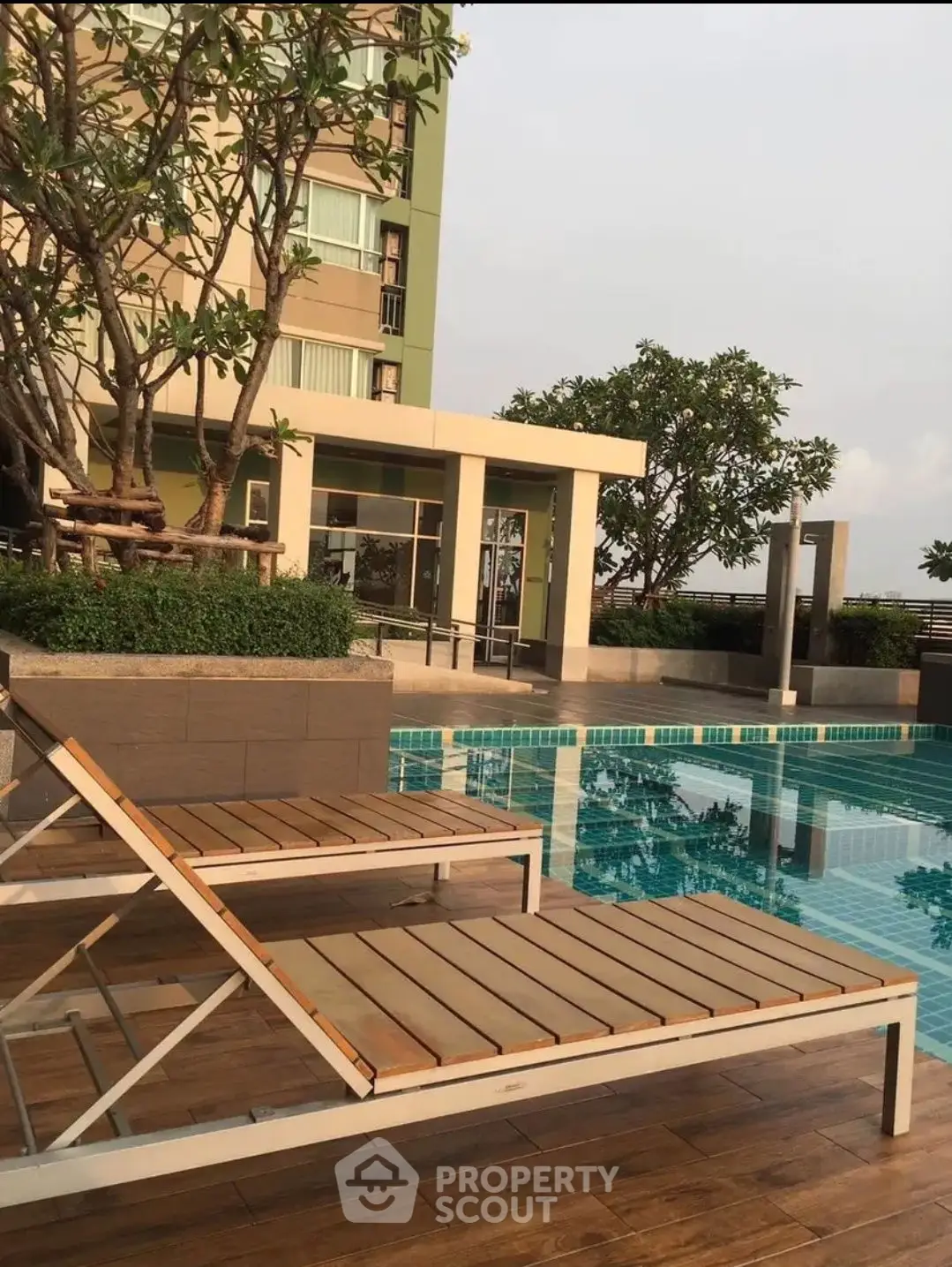 Luxurious poolside area with modern loungers and lush greenery in a high-rise building.