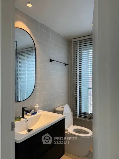 Modern bathroom with sleek fixtures and large mirror, featuring a minimalist design and natural light.