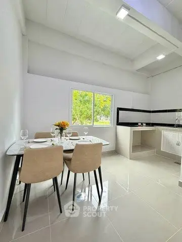 Modern kitchen with dining area, featuring sleek design and natural light.