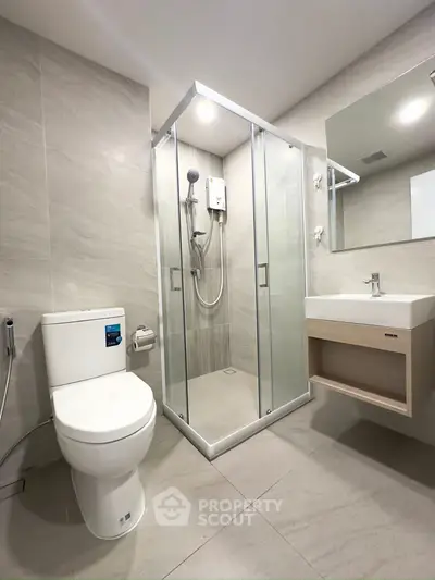 Modern bathroom with glass shower, sleek toilet, and stylish sink in a contemporary setting.