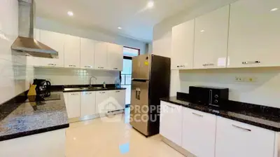 Spacious modern kitchen with sleek white cabinets and granite countertops, featuring stainless steel appliances.