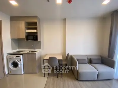 Modern living room with compact kitchen and washing machine in cozy apartment.