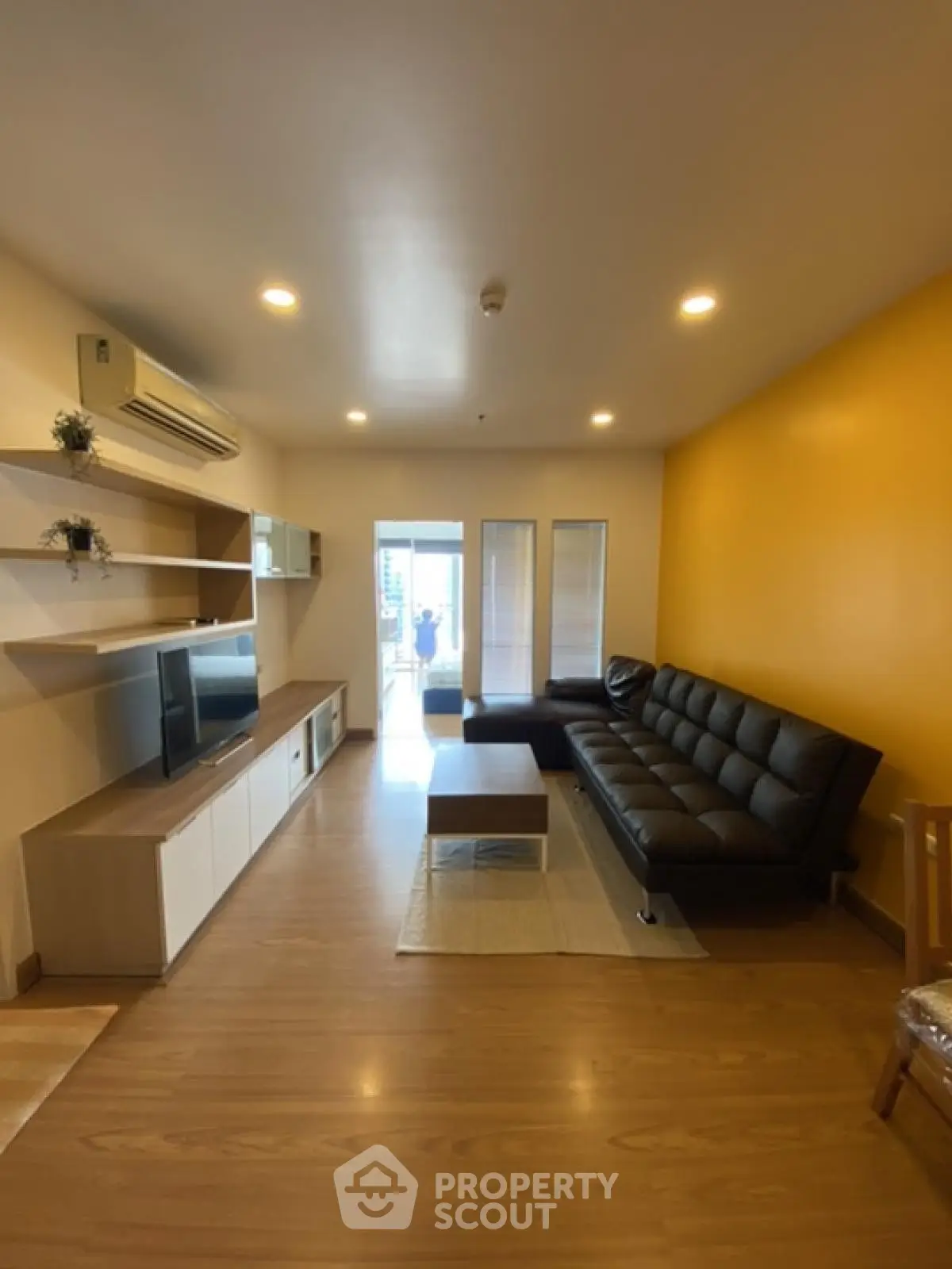 Modern living room with sleek black sofa and wall-mounted TV unit
